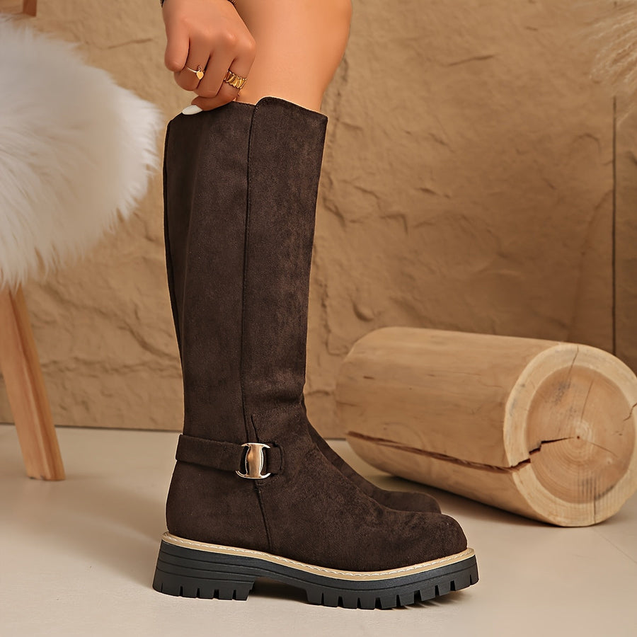 Women's black knee-high boots with suede-look finish, decorative buckle, and lug sole
