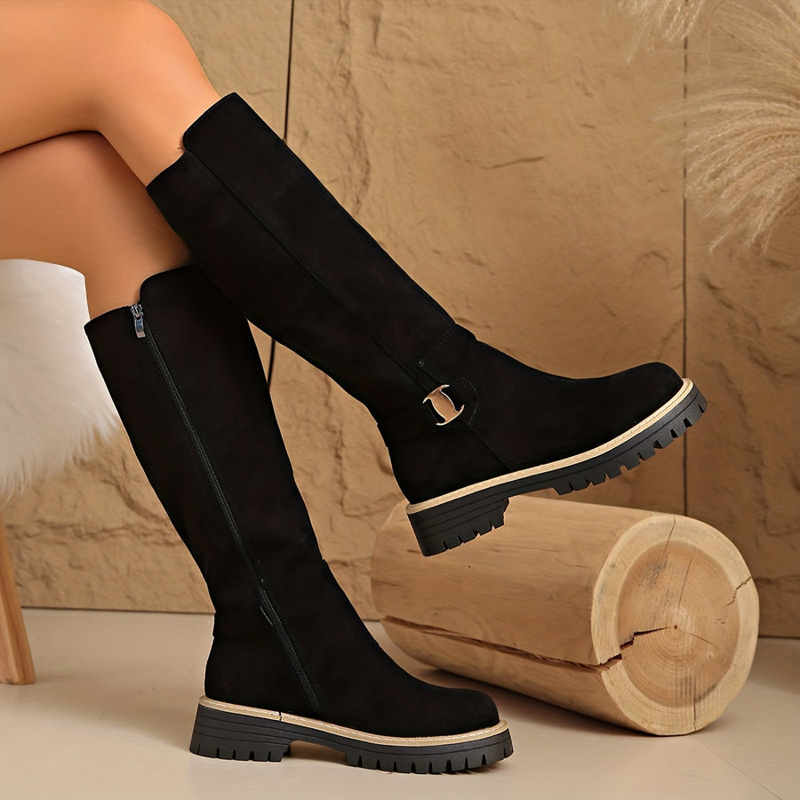 Women's black knee-high boots with suede-look finish, decorative buckle, and lug sole