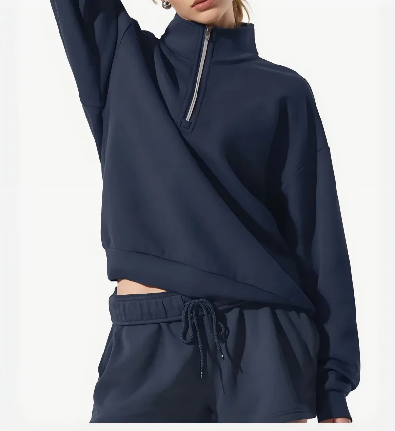 Sportssett for kvinner med sweatshirt med høy krage og glidelås samt lysegrå shorts