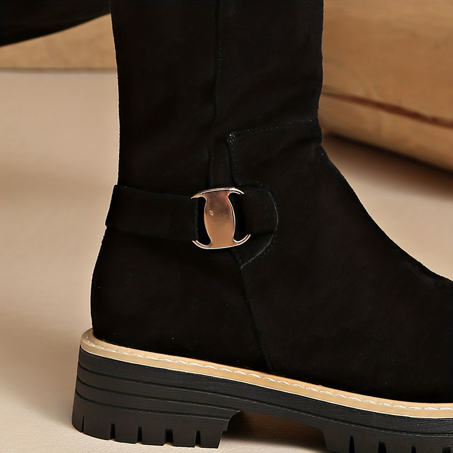 Women's black knee-high boots with suede-look finish, decorative buckle, and lug sole
